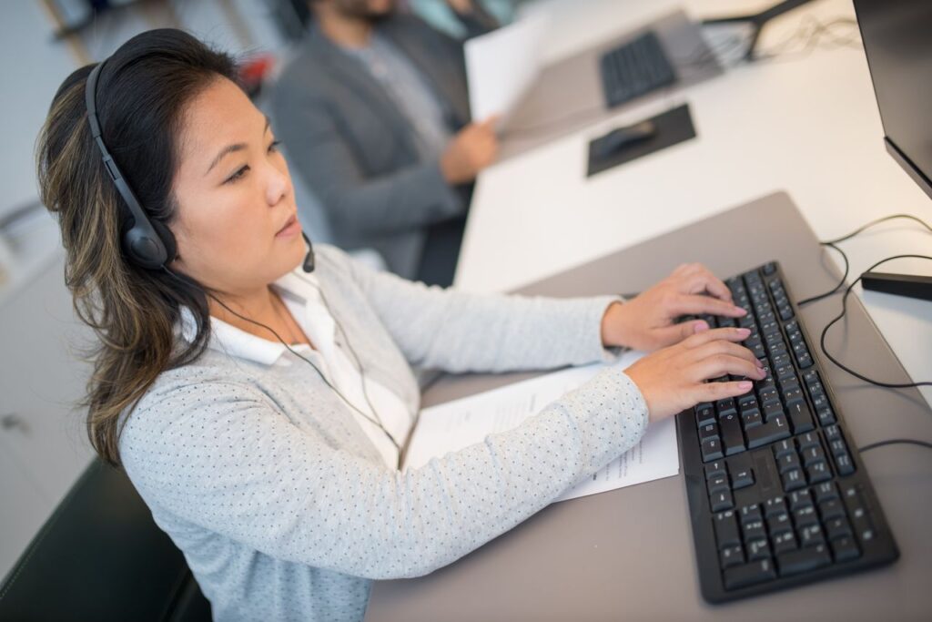 Career Growth in Chat Support | Join the Team at RH Industries Chat support team collaborating in a modern office setting, with a supervisor helping an executive, representing career growth in BPO.